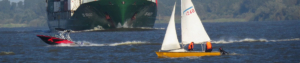 Ein Segelboot auf der Elbe und im Hintergrund nähert sich ein Frachtschiff