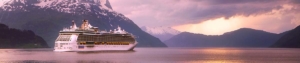 Kreuzfahrtschiff liegt in einem Fjord umringt von hohen schneebedeckten Bergen